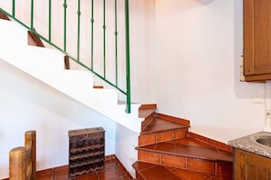 Stairs lead to an upper floor, flanked by a bench and a stool.