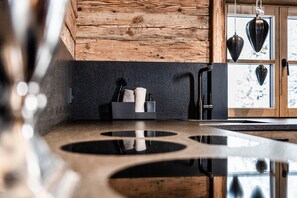 Une cuisine avec un plafond en bois, un plan de travail noir et des ustensiles de cuisine suspendus.