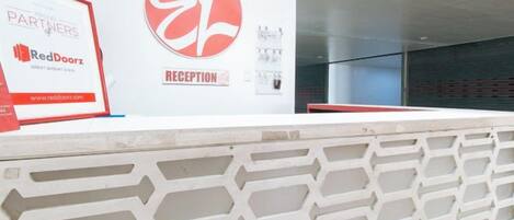Una mesa de recepción con un letrero de RedDoorz, un área de recepción y una pared con un logotipo.