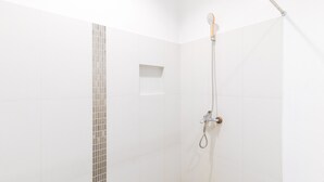 A shower with a handheld showerhead and a wall-mounted faucet.