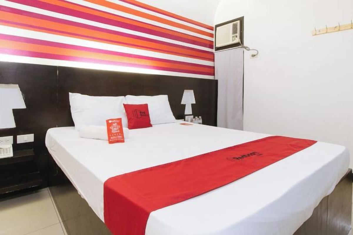 Une chambre d’hôtel avec un lit, une table de chevet, une lampe et un mur à rayures.