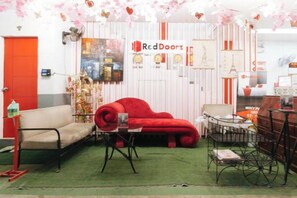 Una habitación con un sofá rojo, un sillón beige, una mesita pequeña y una bicicleta.