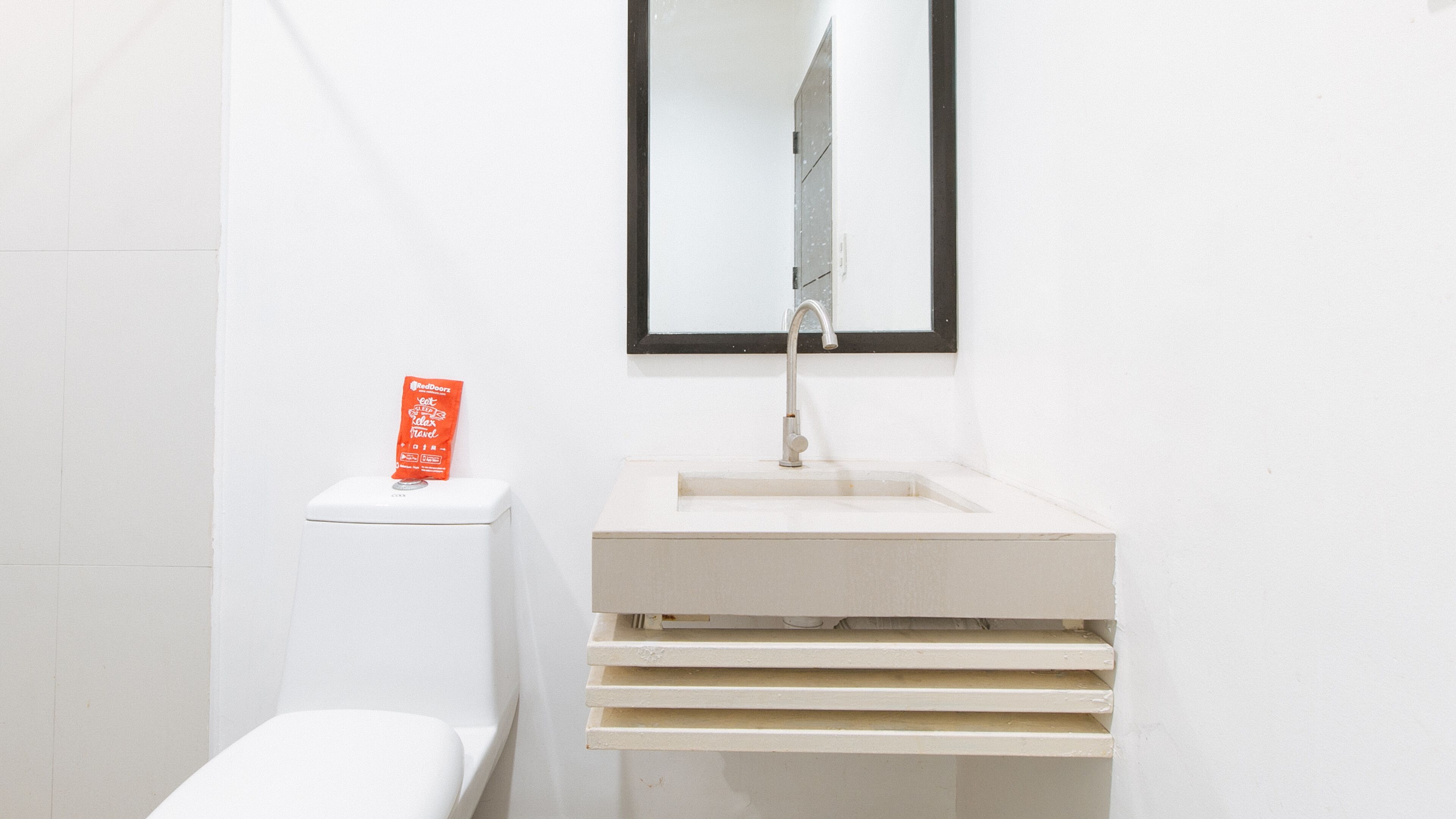 A bathroom with a white sink, a mirror above it, and a toilet.