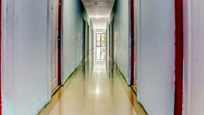 A long, narrow hallway with doors on both sides, leading to a bright area at the end. - Super OYO 3903 Sweethome Syariah Guesthouse (Banjarbaru)