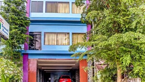 A multi-story building with a blue facade and a red car parked in the garage. - Super OYO 3903 Sweethome Syariah Guesthouse (Banjarbaru)