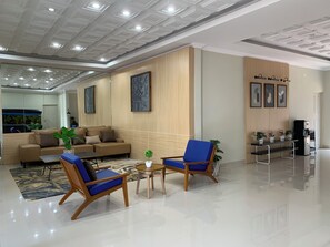 A modern lobby with a sofa, two armchairs, a coffee table, and a small plant.