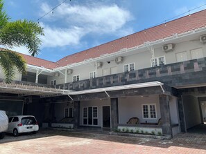 A multi-story building with a red-tiled roof, air conditioning units, and a covered outdoor seating area.