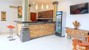 Une cuisine moderne dotée d’un îlot central, de meubles en bois, d’un réfrigérateur encastré et d’un coin bar avec des tabourets.