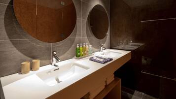 A modern bathroom with two sinks, a large mirror, and toiletries on the counter.