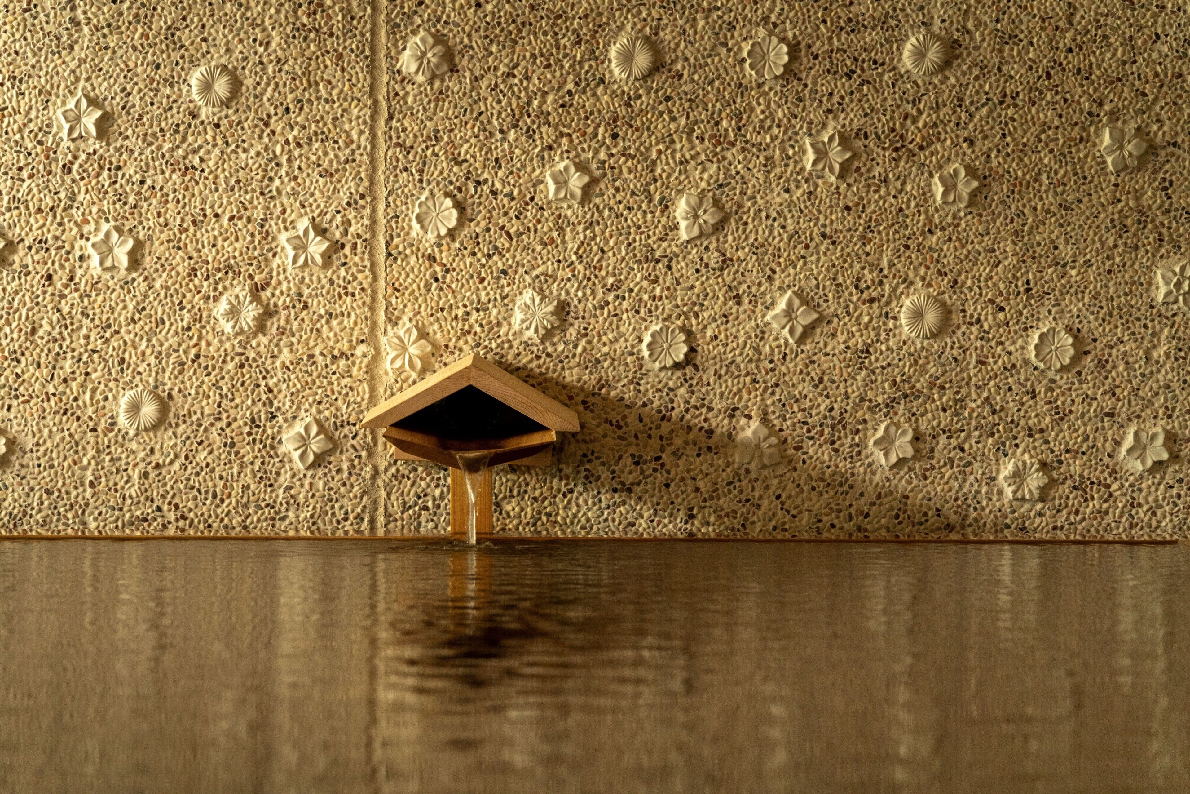 A textured wall with embedded floral designs and a wooden structure.