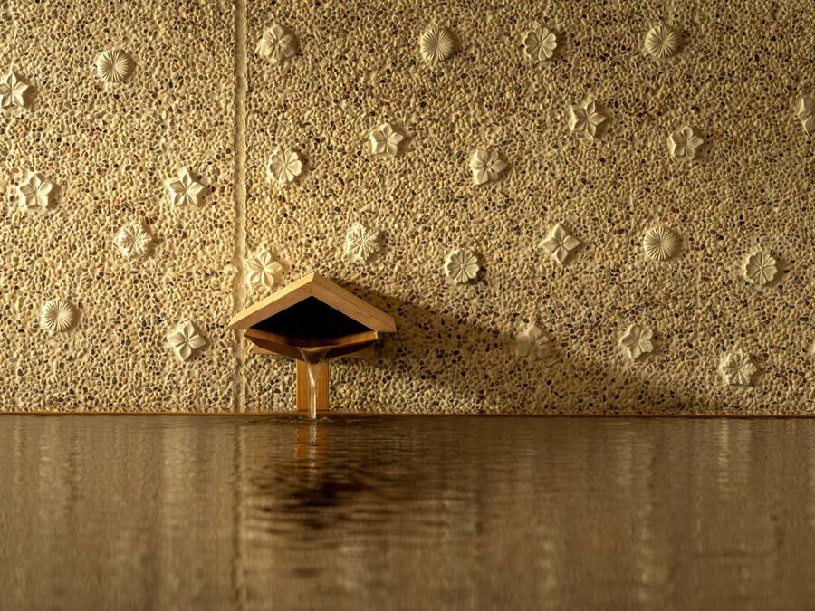 A textured wall with embedded floral designs and a wooden structure.