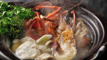 Un tazón de sopa de mariscos con diversos ingredientes como camarones, champiñones y vegetales de hoja.