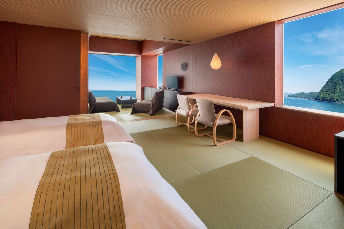 Een moderne hotelkamer met twee bedden, een bureau en uitzicht op zee.