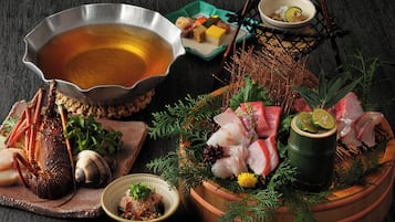 A variety of seafood and a bowl of soup on a wooden table.