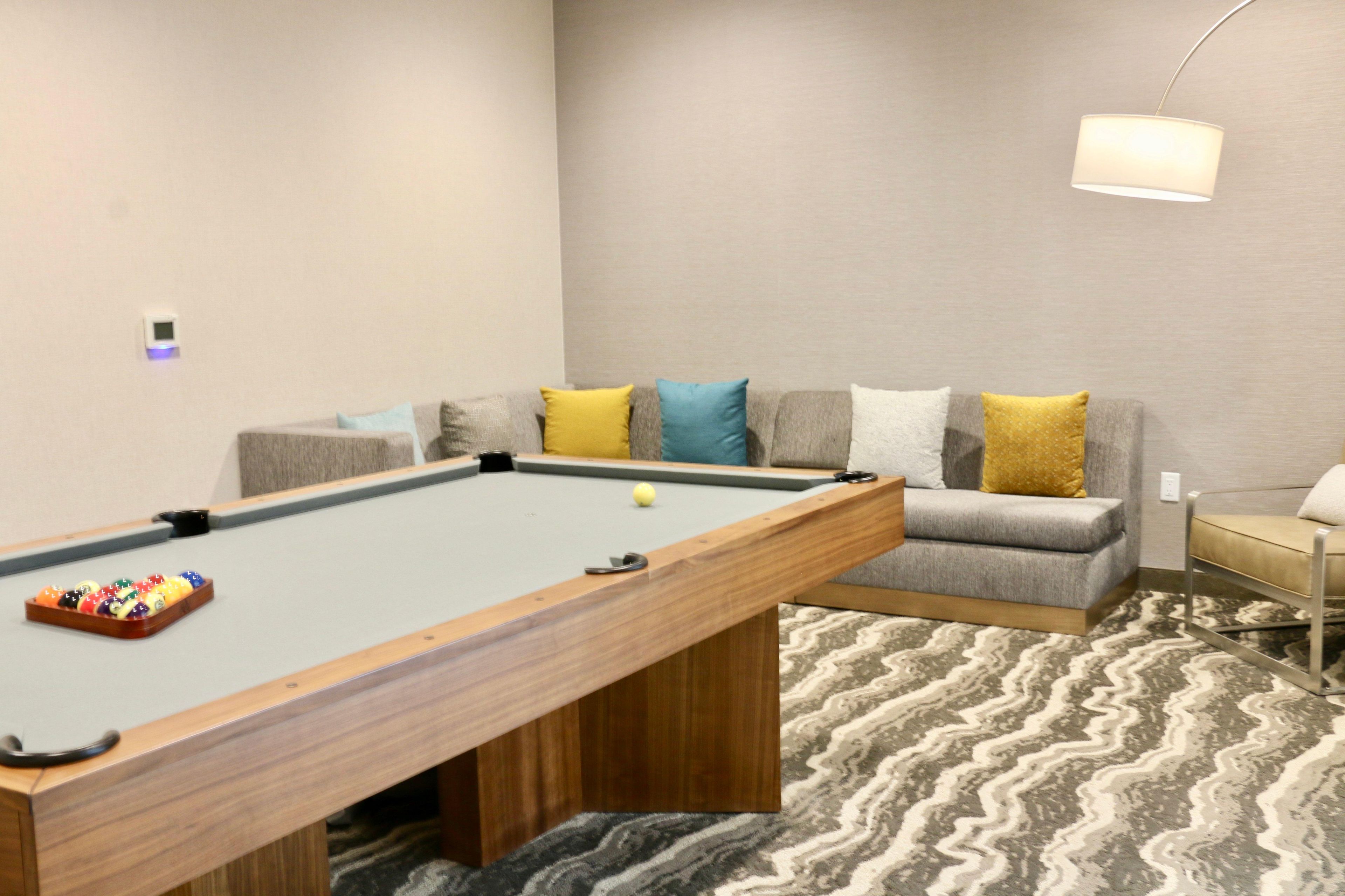 A pool table with balls, a sofa with cushions, and a lamp.