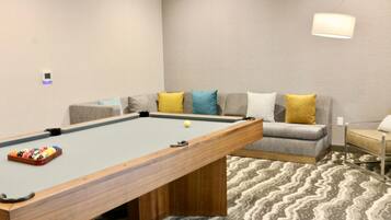 A pool table with balls, a sofa with cushions, and a lamp.