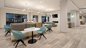 Moderni hotellin aula, jossa on oleskelualue, takka ja taulutelevisio.