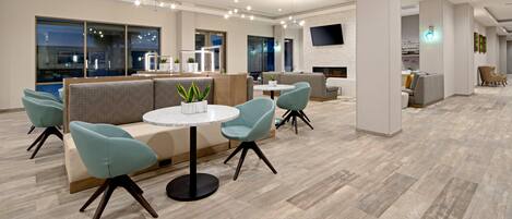 A modern hotel lobby with a seating area, a fireplace, and a flat-screen TV.