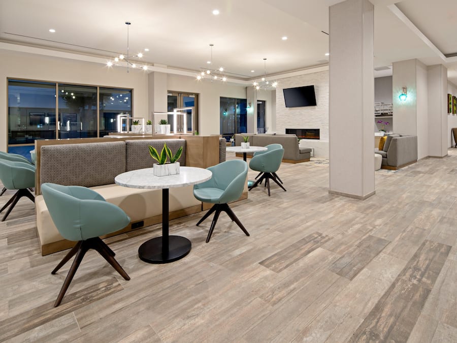 Een moderne hotel lobby met een zithoek, een open haard en een flatscreen televisie.