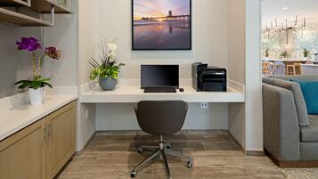 A modern office space with a desk, chair, and a large framed picture of a sunset pier.