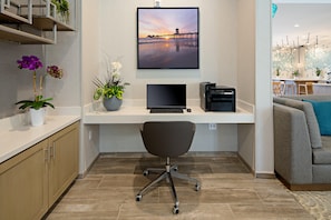 A modern office space with a desk, chair, and a large framed picture of a sunset pier. - Staybridge Suites Long Beach Airport (Long Beach)