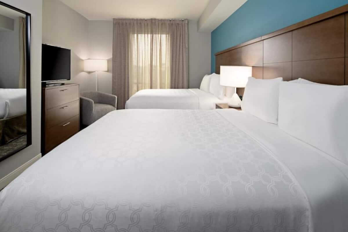 Quarto de hotel com duas camas, televisão, secretária e uma cadeira.