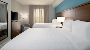 Ein Hotelzimmer mit zwei Betten, einem Fernseher, einem Schreibtisch und einem Stuhl.