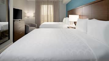 Ett hotellrum med två sängar, en tv, ett skrivbord och en stol.