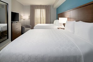 Une chambre d’hôtel avec deux lits, une télévision, un bureau et une chaise.