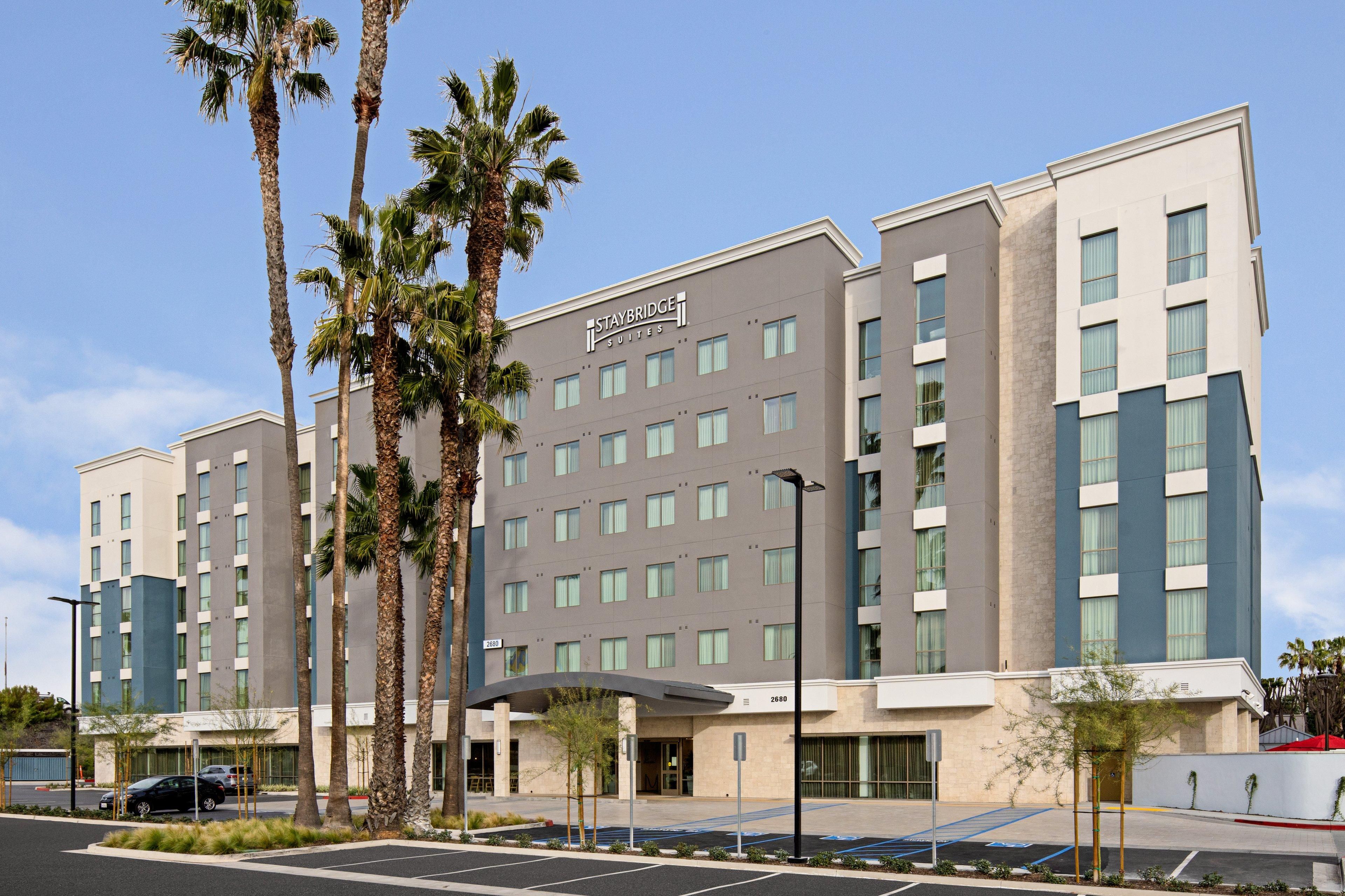 A Staybridge Suites hotel with a modern facade, multiple floors, and a parking area with marked spaces.
