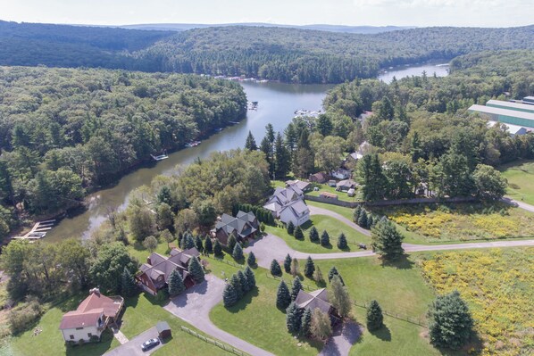 An aerial view of a residential area with houses, a river, and a forested landscape.