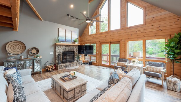 A spacious living room with a fireplace, comfortable seating, and large windows. - Family Lake Retreat w/ Fire Pit & Hot Tub (Swanton)