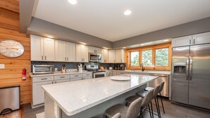 A modern kitchen with a large island, stainless steel appliances, and wooden accents. - Family Lake Retreat w/ Fire Pit & Hot Tub (Swanton)