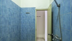 A bathroom with blue tiles, a shower with a hose, and a door leading to another room. - Spot ON 3978 Hotel Danau Indah (Bekasi)