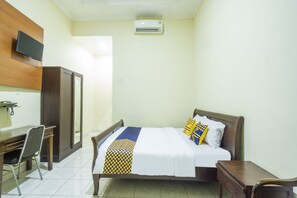 A hotel room with a bed, a desk, a chair, a television, and an air conditioning unit. - Spot ON 3978 Hotel Danau Indah (Bekasi)