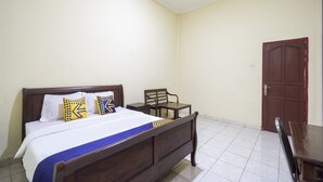 A bedroom with a wooden bed, a chair, a small table, and a door. - Spot ON 3978 Hotel Danau Indah (Bekasi)
