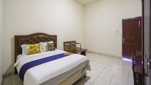 A bedroom with a bed, a chair, a wooden door, and a tiled floor. - Spot ON 3978 Hotel Danau Indah (Bekasi)