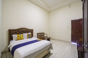 A bedroom with a bed, a chair, a wooden door, and a tiled floor. - Spot ON 3978 Hotel Danau Indah (Bekasi)