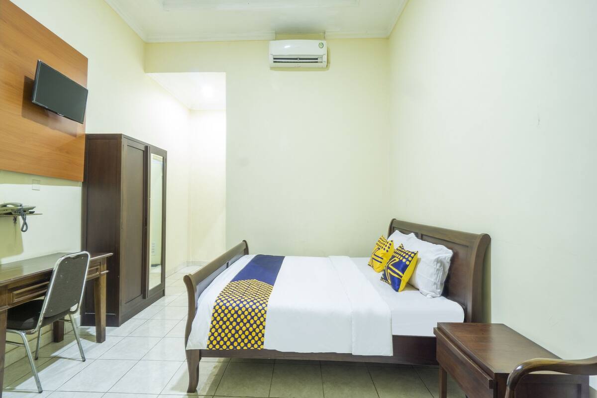 Une chambre d’hôtel équipée d’un lit, d’un bureau, d’une chaise, d’une télévision et d’un appareil de climatisation.