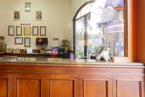 A reception desk with framed certificates, a television, and a reception sign. - Spot ON 3978 Hotel Danau Indah (Bekasi)