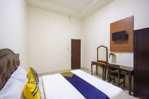A hotel room with a bed, a desk, a chair, a TV mounted on the wall, and a door. - Spot ON 3978 Hotel Danau Indah (Bekasi)