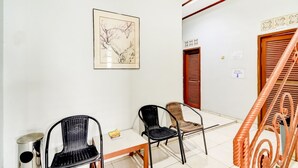 A room with a white wall, a framed artwork, a wooden table, and two black chairs.