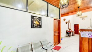 A reception area with a waiting area, wooden ceiling, and a signboard.