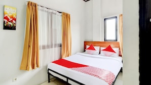 A bedroom with a bed, curtains, a window, and a painting on the wall.