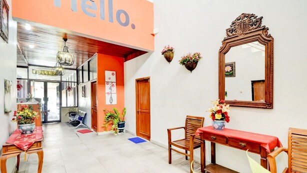 A hotel lobby with a red and white color scheme, a wooden reception desk, and a large mirror on the wall.