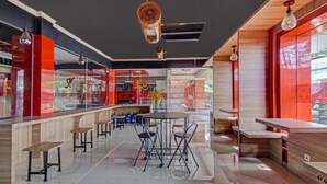 Een modern restaurant met een centrale eetruimte, een bar en uitzicht op de straat.
