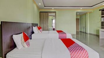 A hotel room with two beds, a wooden headboard, a mirror, and a bathroom visible through a glass door.