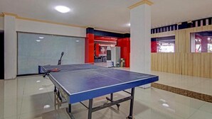 Een tafeltennistafel in een kamer met een betegelde vloer, een grote spiegel en een muur in rood en blauw.