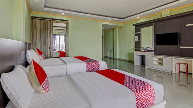 Een hotelkamer met twee bedden, een bureau, een televisie en een badkamer.
