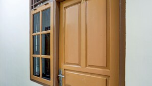 A closed wooden door with a metal handle and a window with multiple panes. - Super OYO 3767 Permata House (Jakarta)